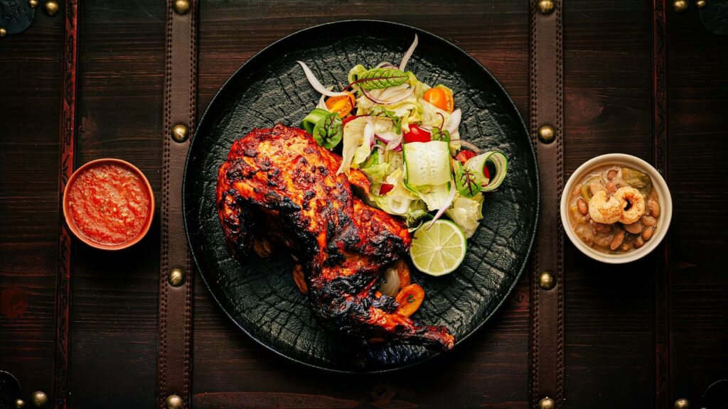 Tandoori-style grilled chicken with fresh salad, lime and dipping sauce, a high-protein desi meal for training