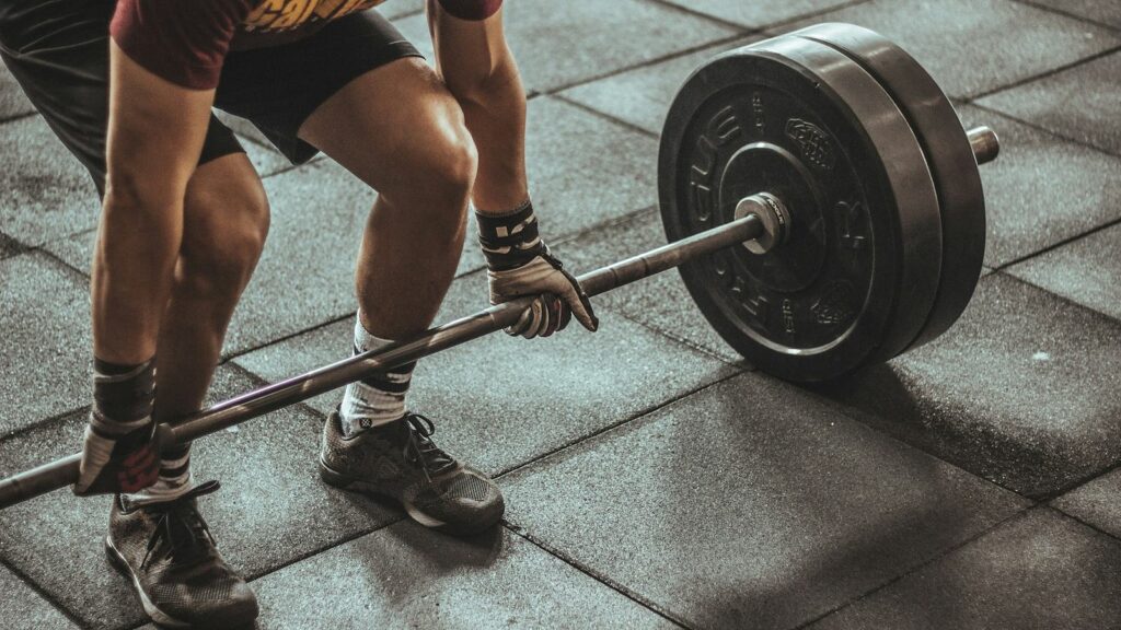 Lifter setting up a barbell deadlift with a flat back and the bar close to the shins on a gym floor