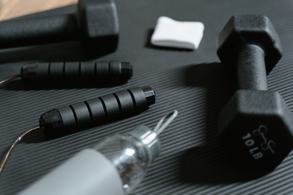 Dumbbells, skipping rope and a water bottle on a gym mat