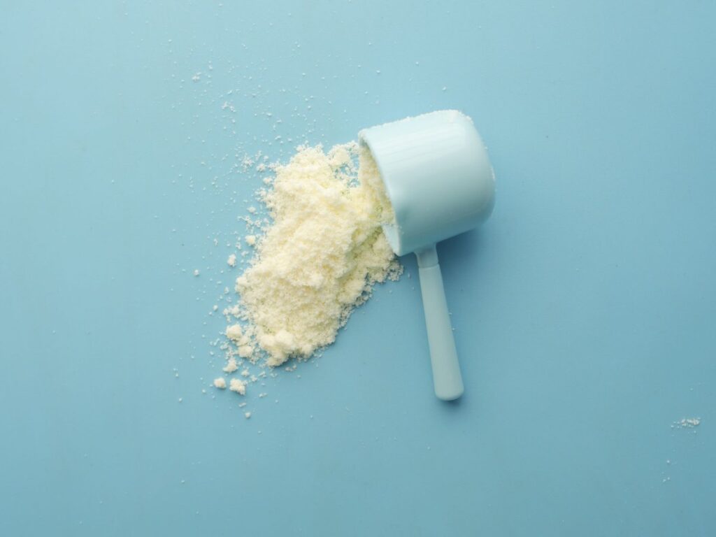 Creatine powder spilling from a scoop on a blue background
