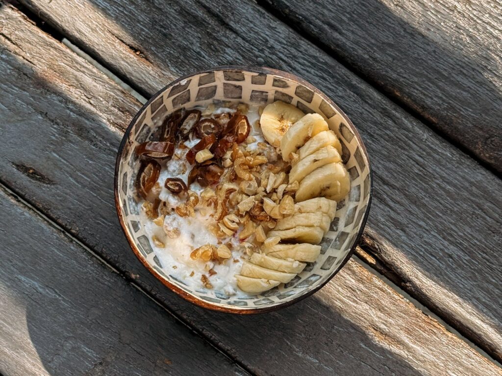 Bowl of oats with banana slices, dates and walnuts as a pre-workout meal.